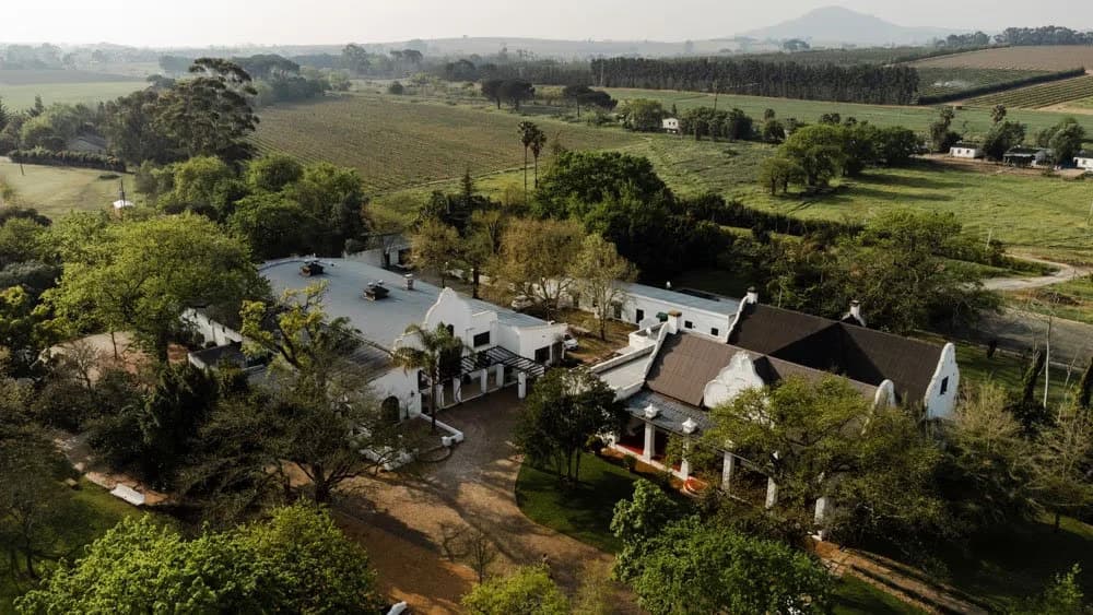 Aerial view of the Nooitgedacht Estate homestead surrounded by vineyards and gardens, Stellenbosch